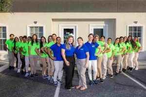 A group of women in green shirts posing in front of a building, with a 20% OFF sign prominently displayed as an exit intent.
