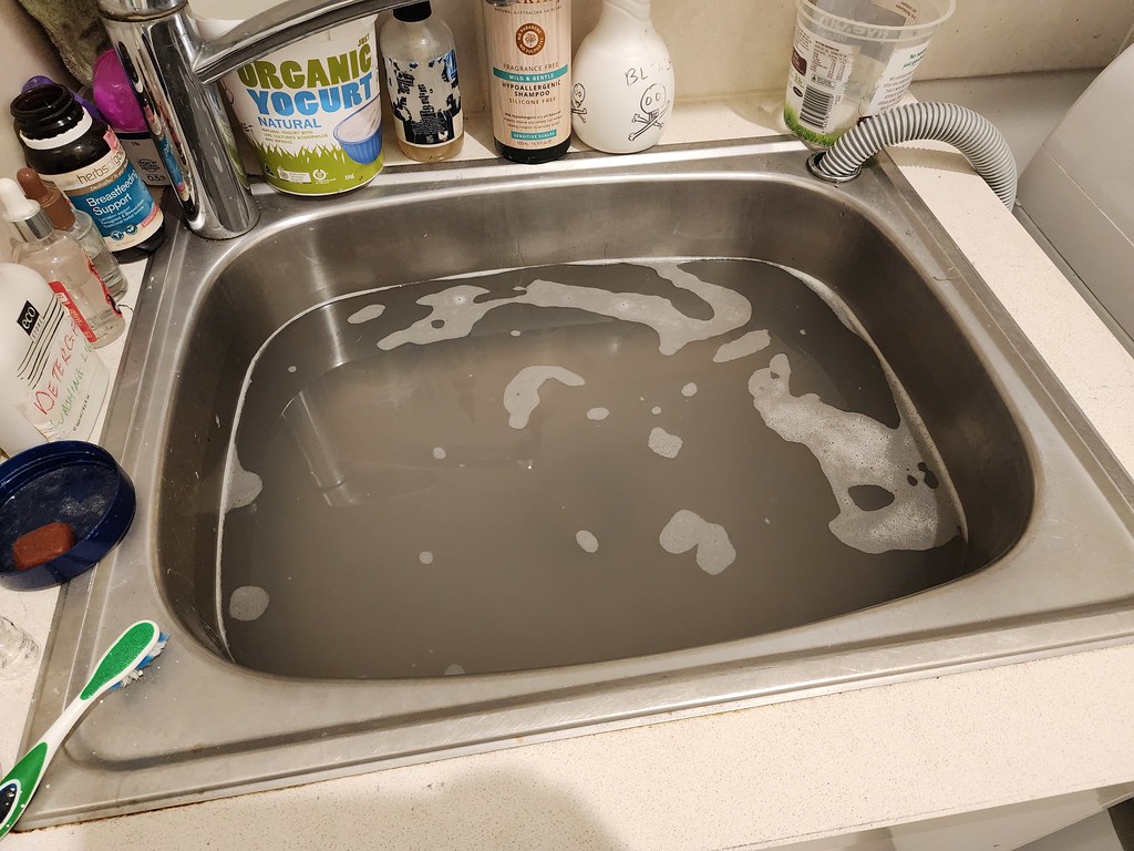 Laundry tub full of rinse water from the washing machine - clogged drains - close