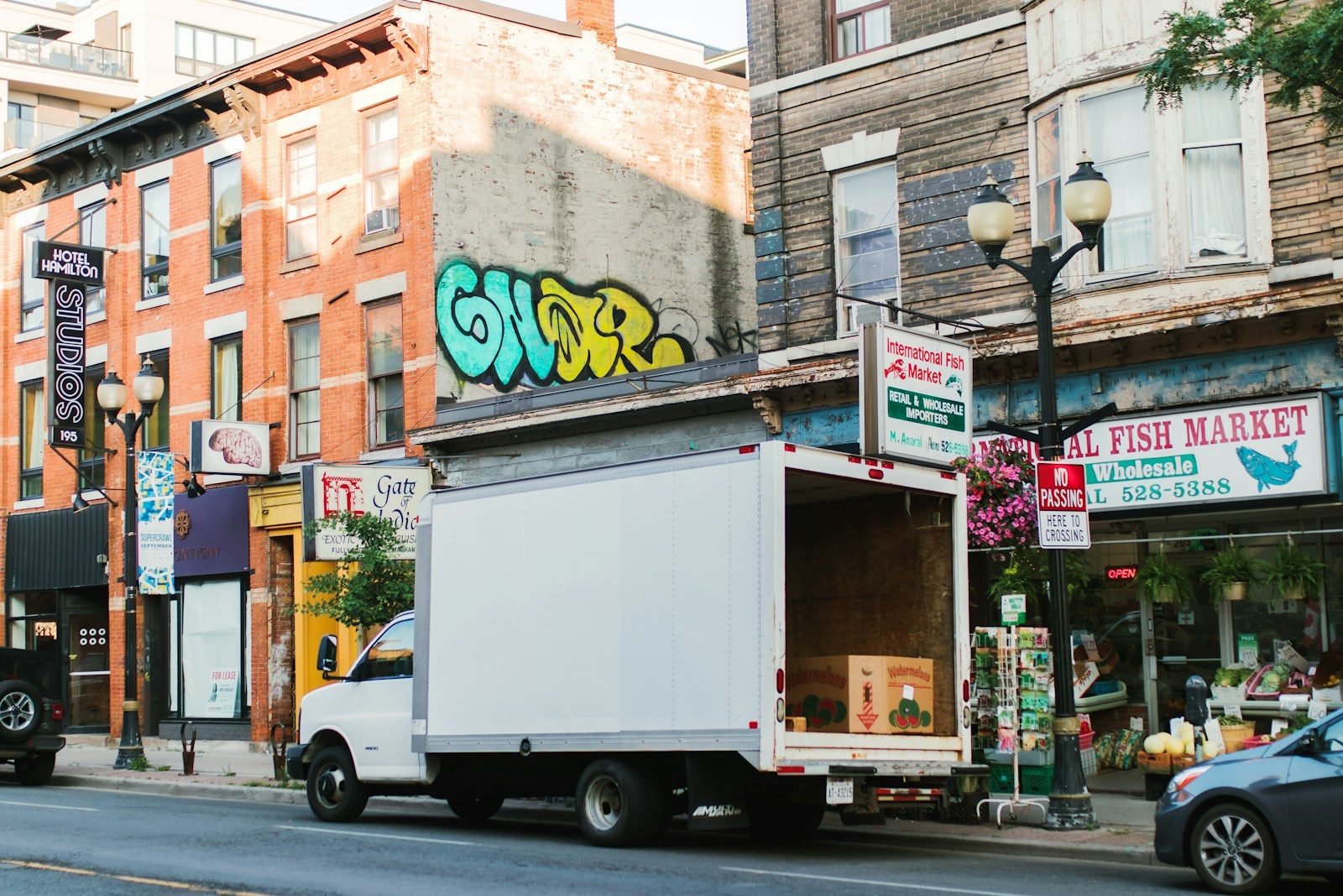 White truck parked on a city street with shops.